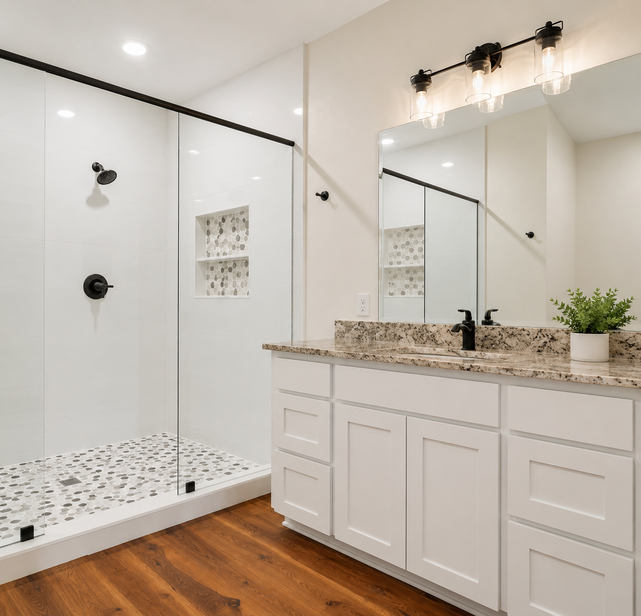 Primary bathroom with frameless glass walk-in shower, pebble tile floor and granite vanity