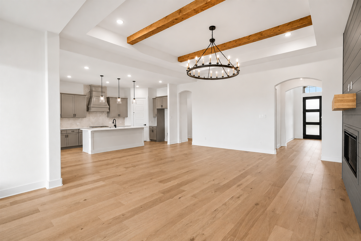 Open concept living and chef's kitchen with white oak floors, gray cabinetry and wood beam ceiling
