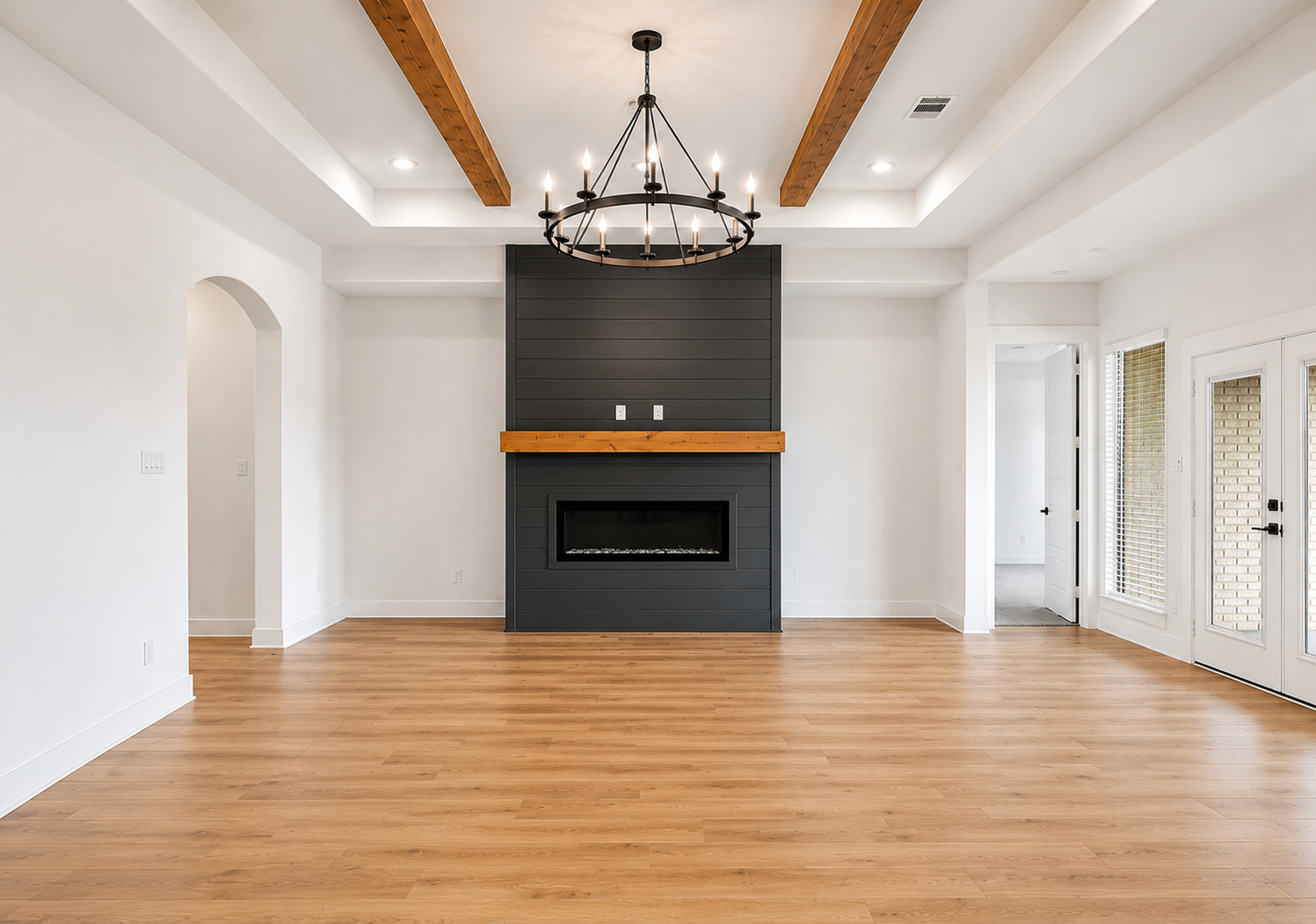 Custom great room with vaulted ceiling, wood beams, black shiplap fireplace and circular candelabra chandelier